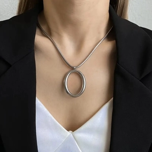 Polished silver snake chain necklace with oval pendant on model wearing a white top