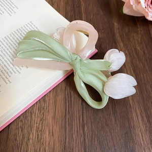 Close-up of pink tulip hair claw clip with silk ribbon bow on a vintage book