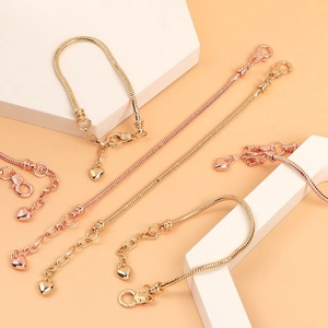 Close-up of gold snake chain with heart charms and lobster clasps on white blocks