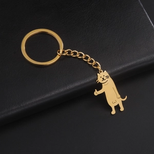 Golden stainless steel keychain with a cute cartoon cat giving a thumbs up on leather background