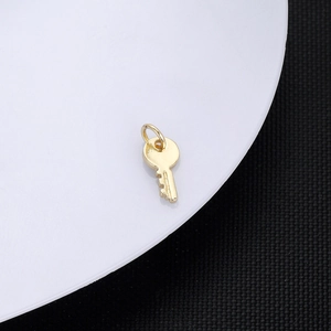 Macro shot of 18K gold plated key pendant with polished finish and integrated ring