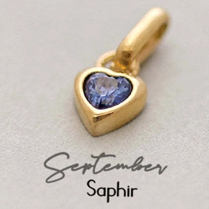Macro shot of gold heart pendant with blue sapphire stone for September birthstone jewelry