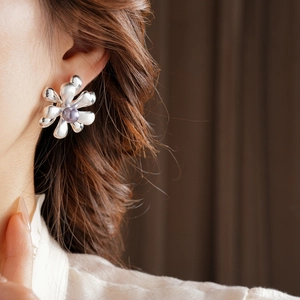 Close-up of 18k gold-plated flower earrings with a silver luster and grey pearl center