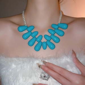Détail du collier de perles blanches laiteuses avec de grosses larmes bleu vif