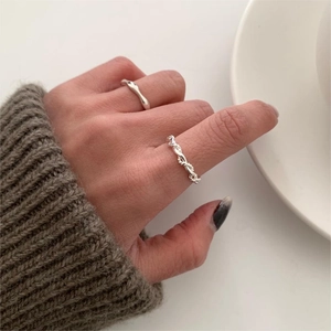 Close-up of minimalist silver twisted rope rings worn on fingers for a stylish look