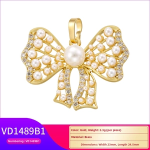 Detail of a brass bow pendant featuring white pearls and cubic zirconia stones