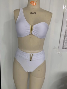 Détail d'un bikini côtelé blanc avec coupe asymétrique et boucle métallique en V doré