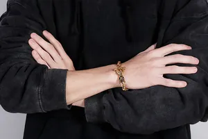 Détail d'un bracelet dragon en acier titane plaqué or 18 carats au poignet d'un homme