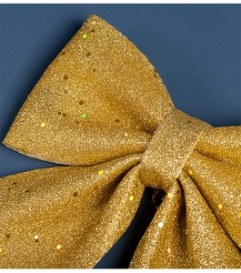 Gros plan d'un grand noeud de Noël doré avec paillettes scintillantes et texture métallique