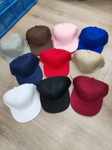 Flat lay of multiple solid color adjustable cotton baseball caps on wooden floor