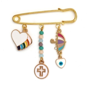 Detailed view of evil eye charms and umbrella pendant on a golden safety pin brooch