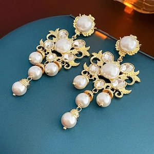 Close-up of golden tassel earrings with white pearls and sparkling crystal details