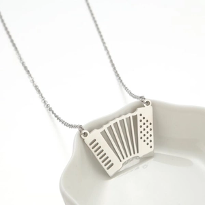 Collier minimaliste avec pendentif accordéon argenté sur une assiette blanche