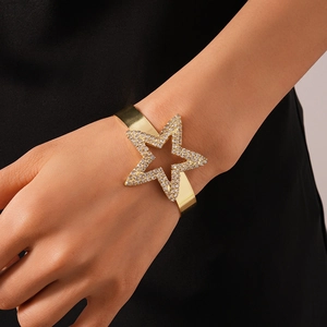 Detail of gold open bangle featuring a large sparkling pavé star on a person's wrist