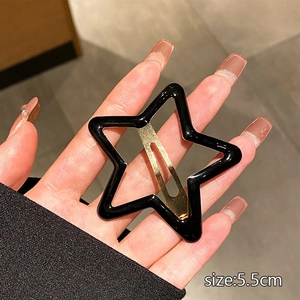Detail view of a 5.5cm hollow star-shaped Y2K hair clip in gold finish held by hand