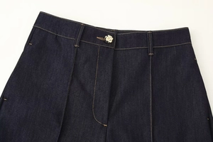 Détail de la taille en denim bleu foncé avec bouton en métal et surpiqûres contrastées