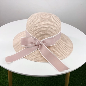 Nahaufnahme von rosa Strohhut mit eleganter Bandschleife auf weißem Tisch platziert