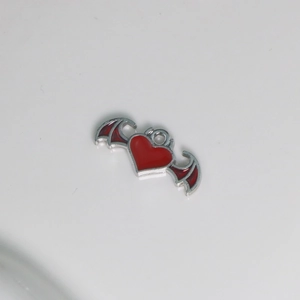 Macro shot of silver-plated bat wing heart pendant with red enamel finish for DIY jewelry