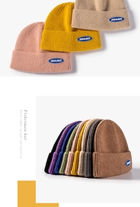 Detail of ribbed knit fisherman beanies with embroidered Orderliness letter patches