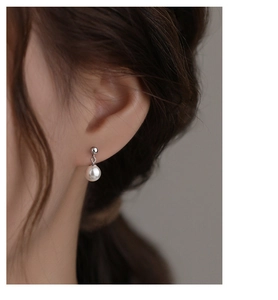Detail of s925 silver earring with elegant pearl drop on a model showing classic French style