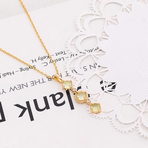 Macro detail of natural prehnite pendant with zircon accents on gold chain necklace