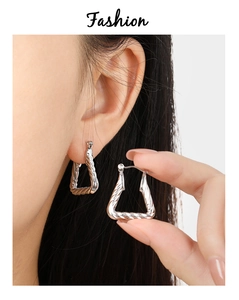 Macro detail of silver twisted rope geometric triangular hoop earrings on model