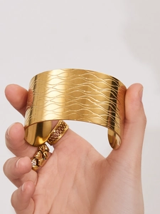 Détail d'un large bracelet en acier inoxydable doré 18k avec texture ondulée