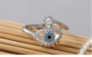 Macro detail of Evil Eye open ring with blue and white stones on wooden background