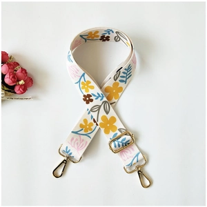 Detail of adjustable floral printed wide strap with gold metal hooks on white background