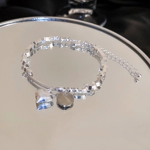 Detail of silver heart charm bracelet with opal and pearl accents on mirror surface