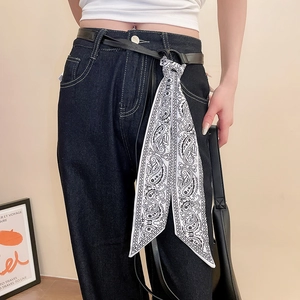 Gros plan d'une ceinture en cuir noir avec un foulard en soie Paisley sur un jean