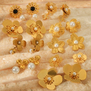 Elegant 18k gold plated flower stud earrings with pearls and black stones on stone surface