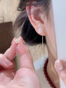 Macro detail of silver snowflake drop earrings with sparkling zircon stones and long chain links
