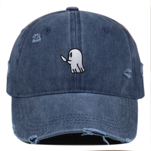 Detail of distressed navy blue denim cap with cartoon ghost embroidery and ripped holes