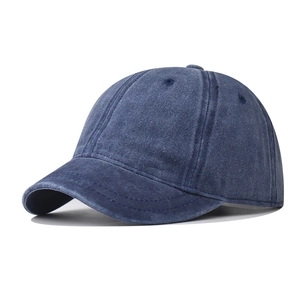 Macro view of washed navy blue cotton baseball cap showing vintage texture and short brim