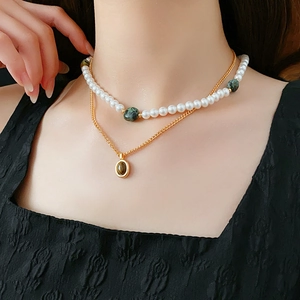 Détail d'un collier de perles superposées avec un pendentif doré sur un mannequin