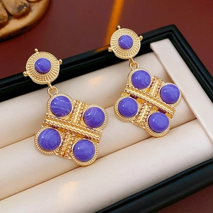 Primo piano di orecchini vintage in oro con pietre viola a cabochon in una scatola