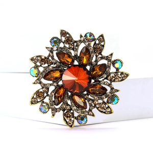 Close-up of vintage flower brooch with reddish-brown gemstone and amber crystals