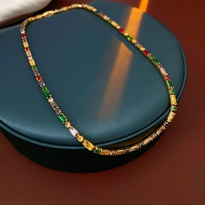 Detail of gold plated necklace with colorful zircon gemstones on a green jewelry box