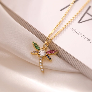Detailed shot of gold dragonfly pendant with colorful zircon stones on white silk background