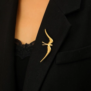 Élégante broche hirondelle en or mat et acier inoxydable sur une veste de costume noire