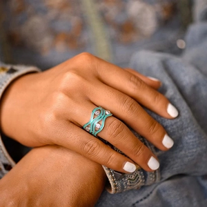Detail van de zilveren ring met golftextuur, groenblauw email en fonkelende zirkoon