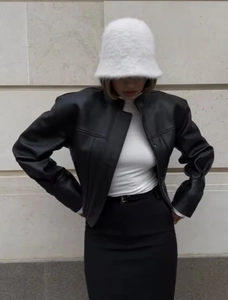 Close-up of stylish black PU leather jacket with white plush bucket hat in streetwear style