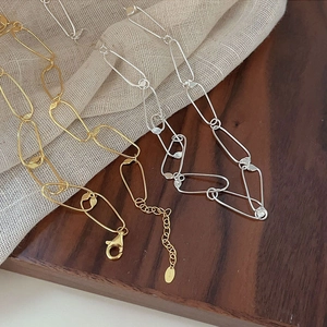 Detailed view of S925 sterling silver paperclip chains in gold and silver on fabric