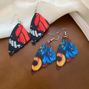 Detailed close-up of acrylic butterfly wing drop earrings with intricate colorful patterns