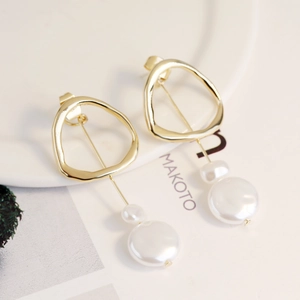 Detail of elegant gold geometric hoop earrings with double baroque white pearls