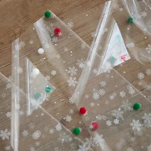 Transparent Christmas snowflake cellophane wrap with colorful pompoms on wood background