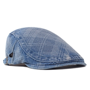 Detail view of denim newsboy cap with diamond quilted texture and metal buckle adjustment