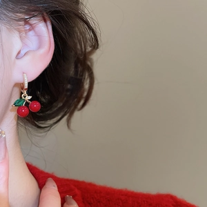 Detail of cherry stud earring with red stones and sparkling diamonds on leaf