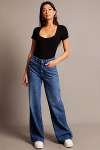Dettaglio di jeans blu a vita alta con gamba larga abbinati a un top nero corto e aderente